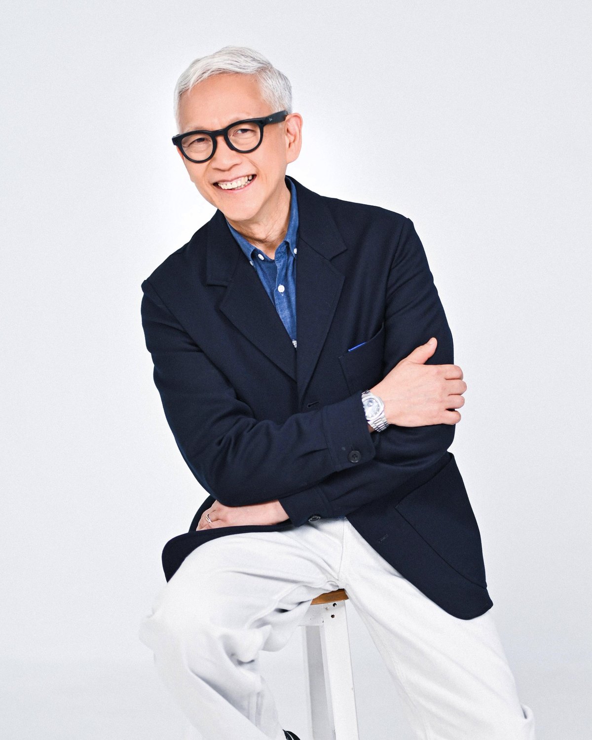 Francis Kong seated and smiling in a navy blazer against a white studio background.